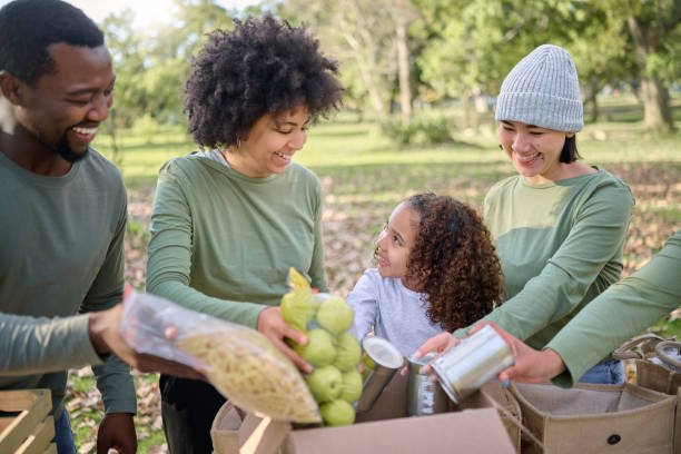 Food donation, volunteering and people with child for sustainability, poverty help and community service in park. Support, teamwork and fruits, vegetable and box for homeless, charity or society care
